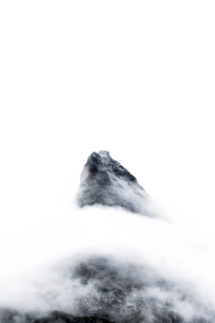 a black and white photo of a mountain in the clouds