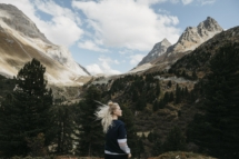 Schweiz, Graubünden, Albulapass, junge Frau mit windzerzaustem Haar in Berglandschaft stehend
