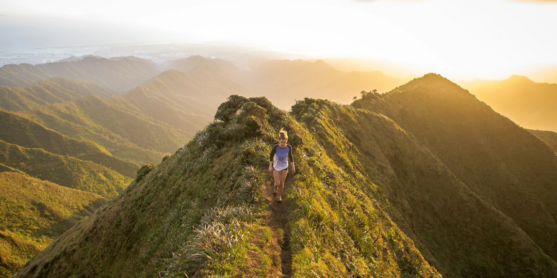woman walking on pathway on top of hill at golden hour