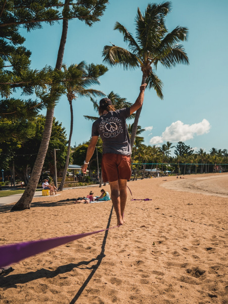 Mann geht tagsüber auf einer Slackline am Meer entlang