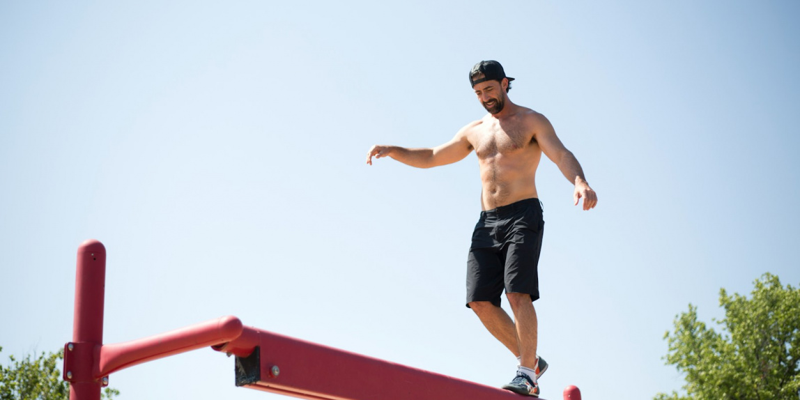 man wearing black shorts walking on red metal beam