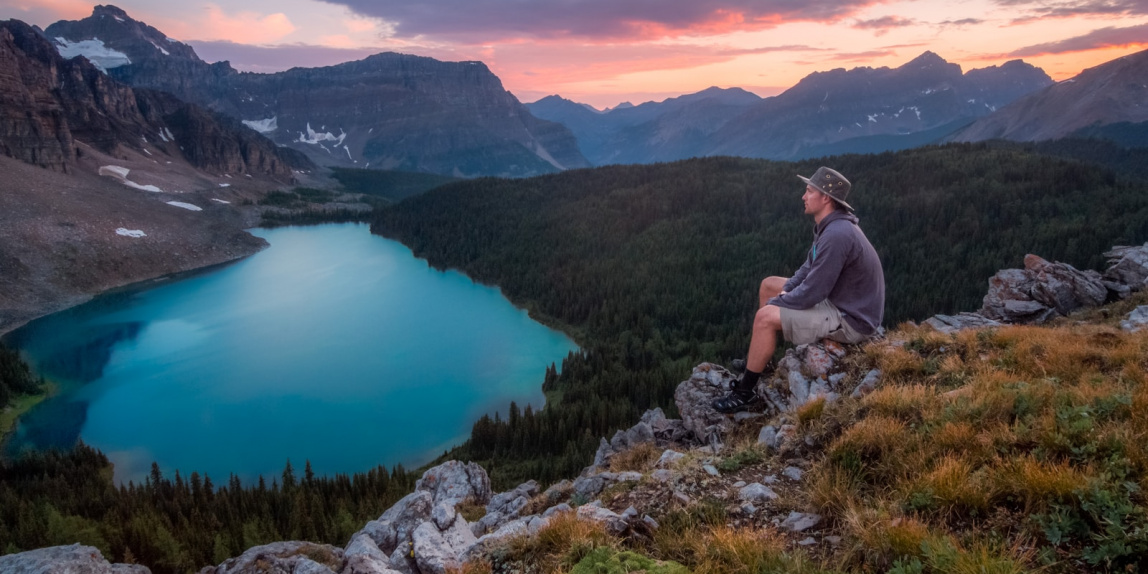 man looking on mountain sitting on rock