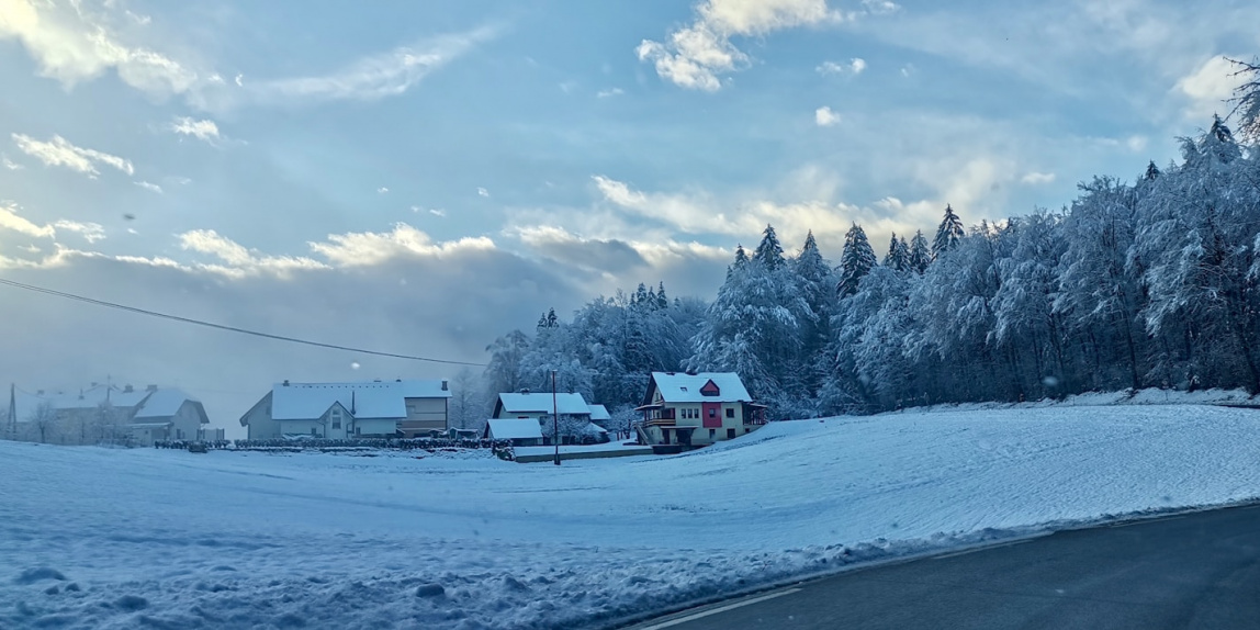 a snow covered road with houses in the distance