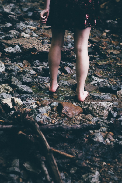 woman standing on rocks with water flowing