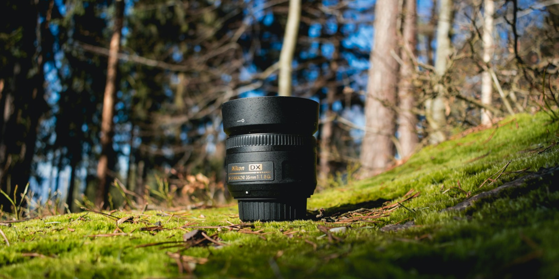 black DSLR lens on green grass shallow focus photography