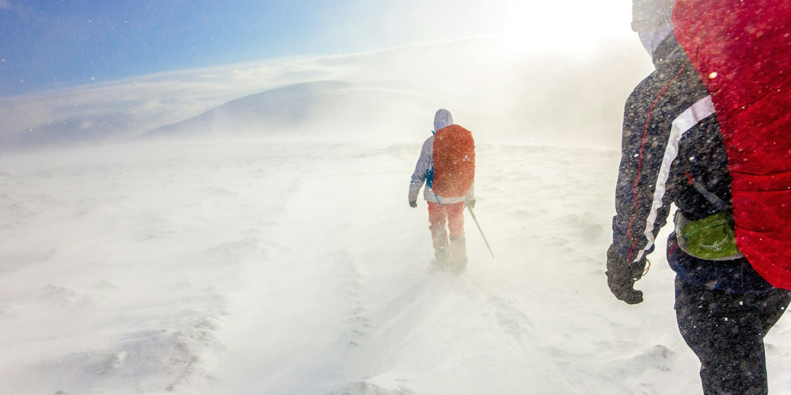 two men walking on snow under blue sky