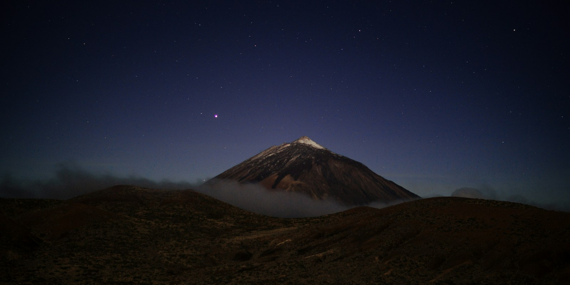 a mountain covered in fog under a night sky