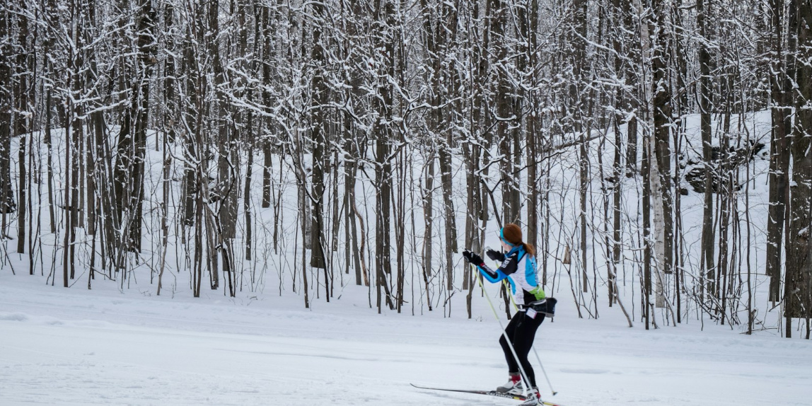 2 person in green jacket and black pants riding ski blades on snow covered ground during