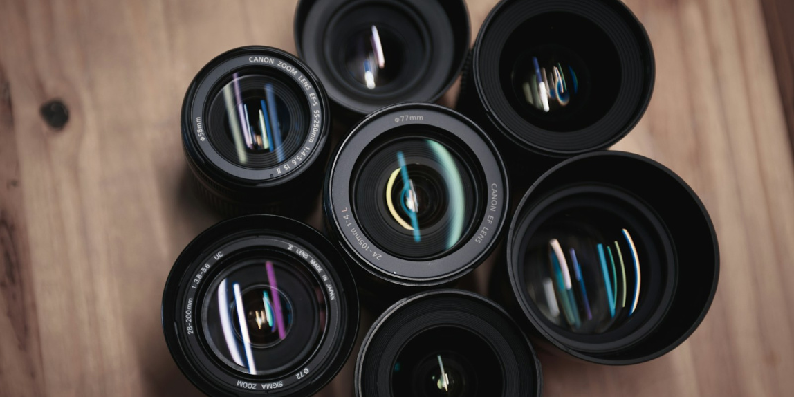 seven black camera zoom lenses on table