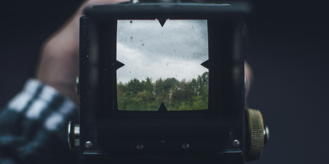 black camera taking photo of green trees during daytime