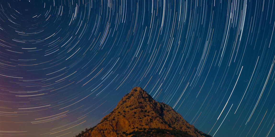 Capturing the mesmerizing star trails over a mountain in Antalya, Turkey under a clear night sky.