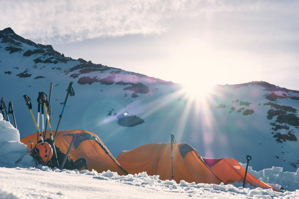 three yellow and red dome tents on snow capped mountain